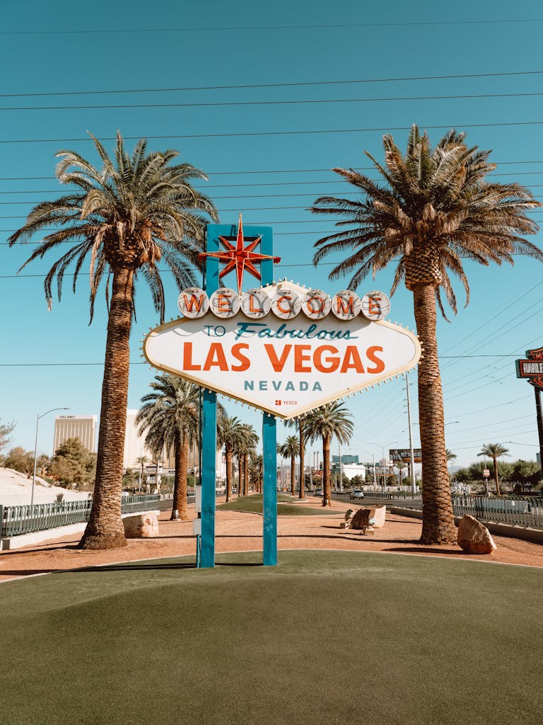 Capture of the famous Welcome to Las Vegas sign surrounded by palm trees under a clear blue sky.